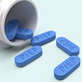 Open pill bottle with blue PrEP pills spilling out